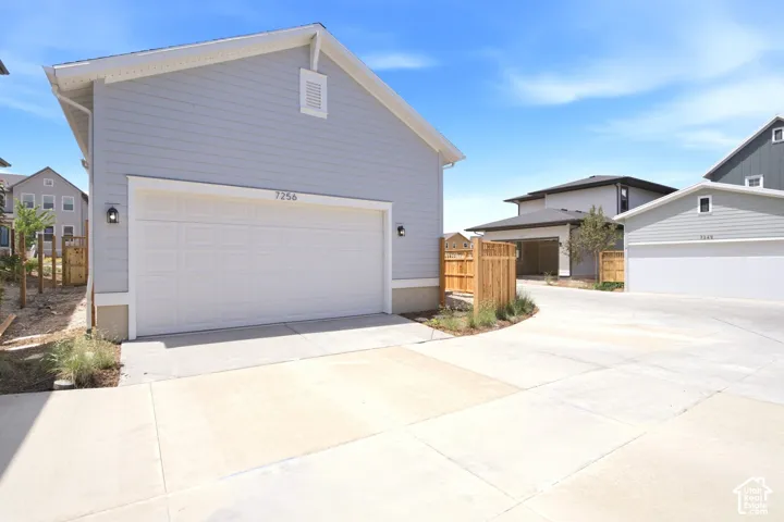 Contemporary exterior siding, attached garage, concrete driveway, and exterior lighting fixtures