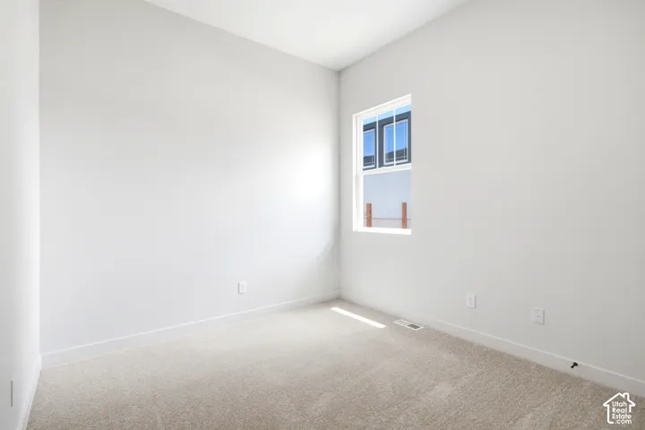 Neutral-toned wall finish, single window with white trim, light-colored carpeting, and white baseboards