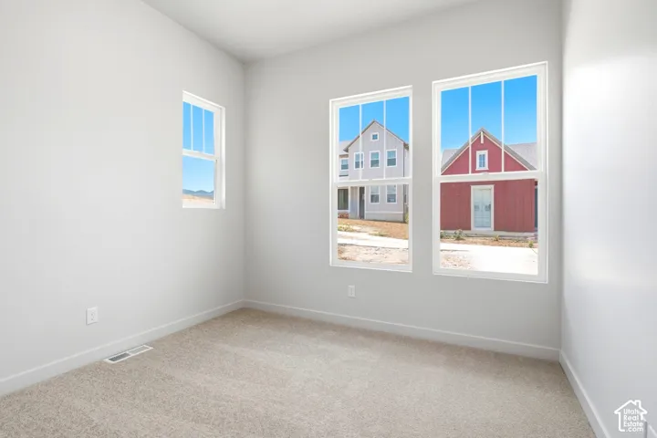 Neutral wall color, three windows, light-colored carpet flooring, and white trim