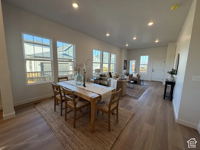 Spacious open-concept living area featuring wood-finish flooring, recessed lighting, and multiple large windows