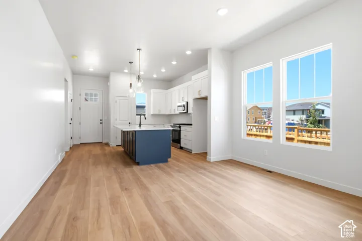 Expansive living area with wood-finish flooring, recessed lighting, and large windows