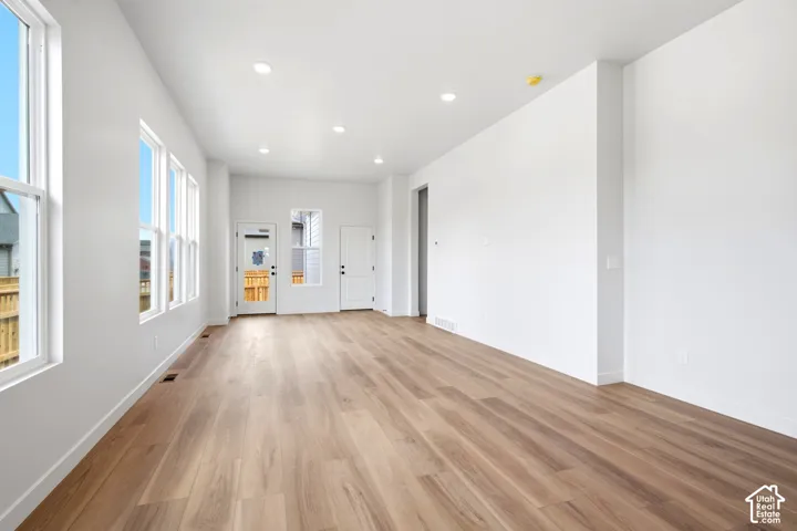Expansive open-concept room featuring wide-plank wood-finish flooring, recessed lighting, and multiple large windows