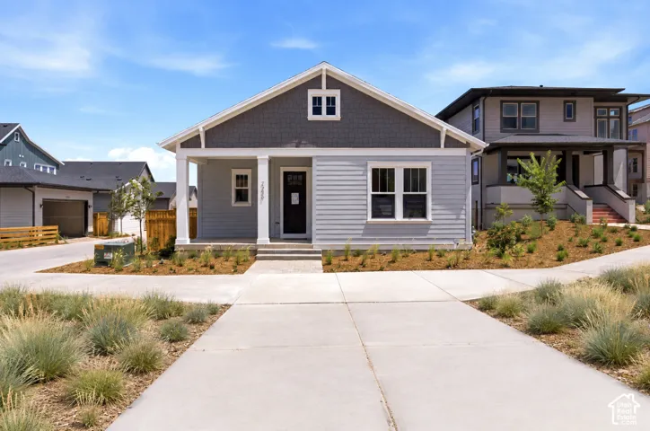 Gable roofline, light gray siding, dark gray shake siding accents, covered front porch with white columns, and a dark entry door