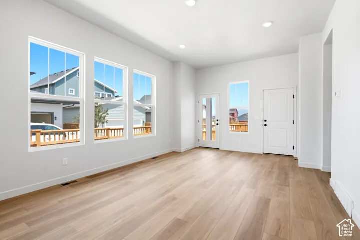 Open concept living area with light wood-finish flooring, recessed lighting, and multiple large windows