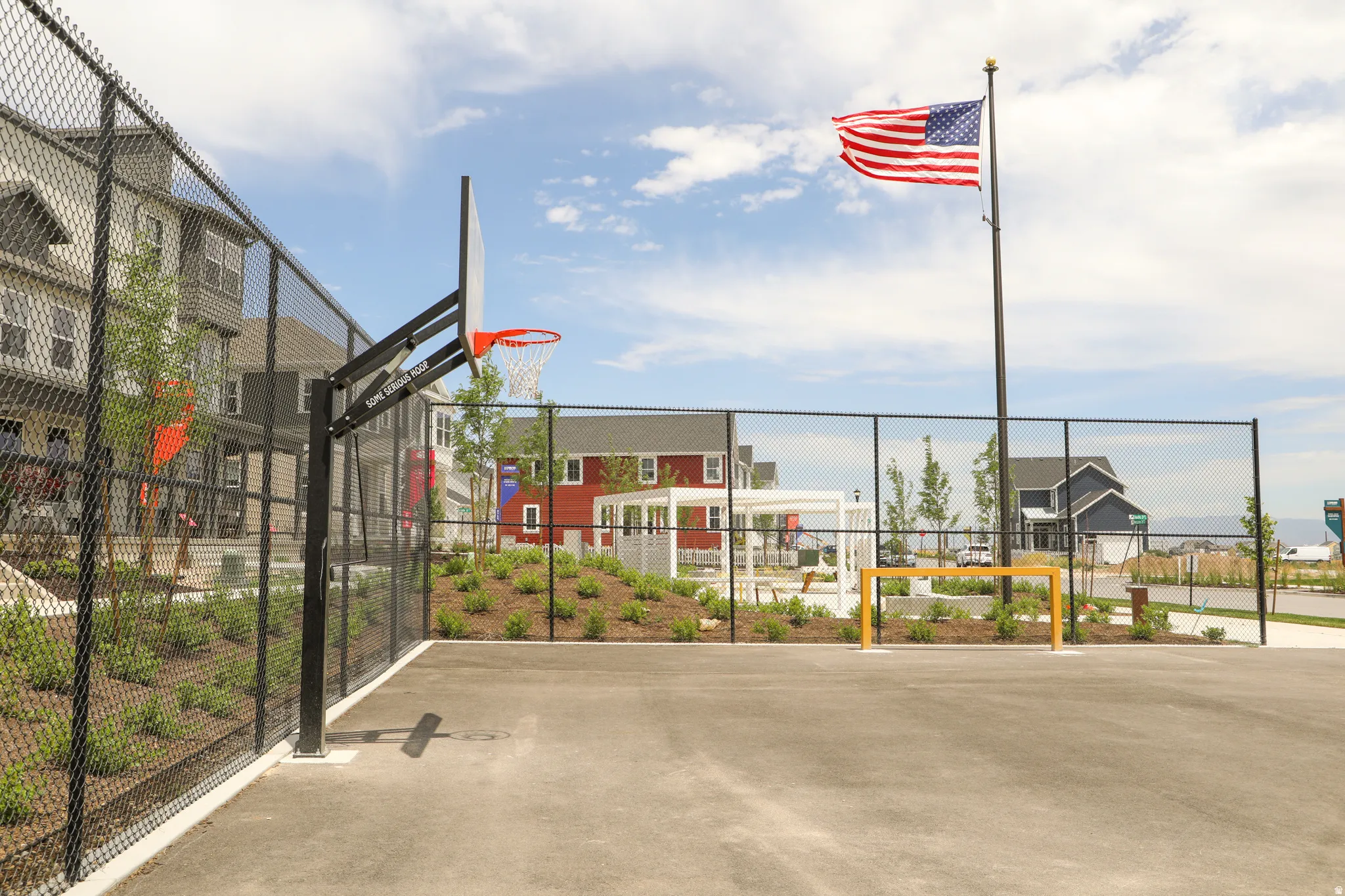 Multi-sport court featuring a basketball hoop and a soccer goal, enclosed by chain-link fencing