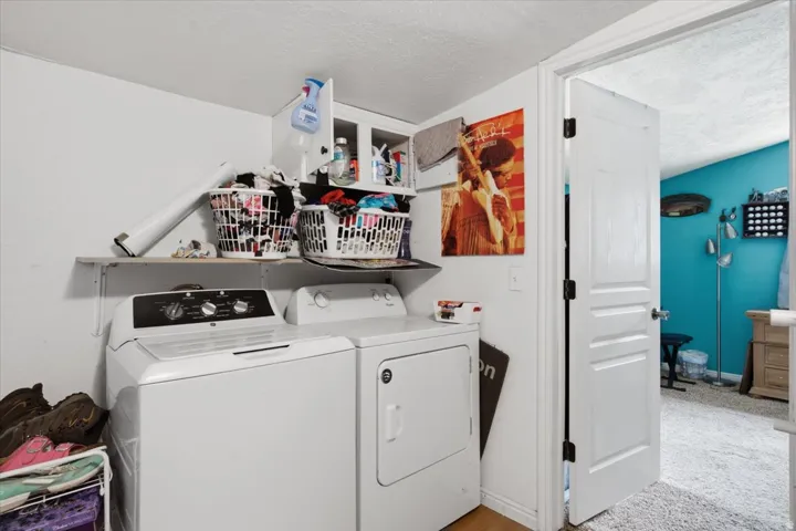 Laundry area featuring built-in shelving, upper cabinetry, and wood-finish flooring