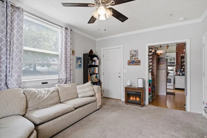 Plush carpeted flooring, a ceiling fan with integrated lighting, and an electric fireplace