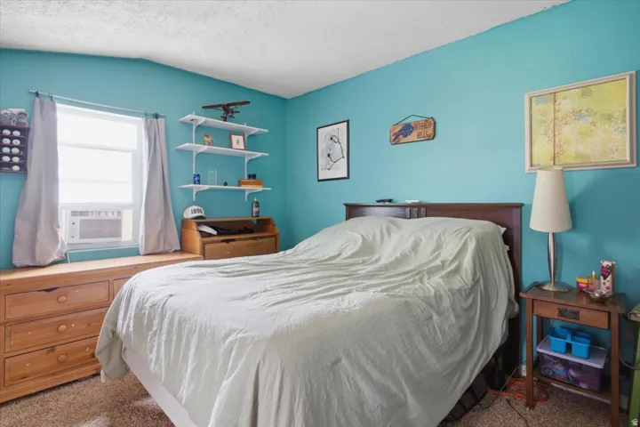 Built-in window seat with integrated drawer storage, bright window, wall-mounted shelving, and wood-finish headboard