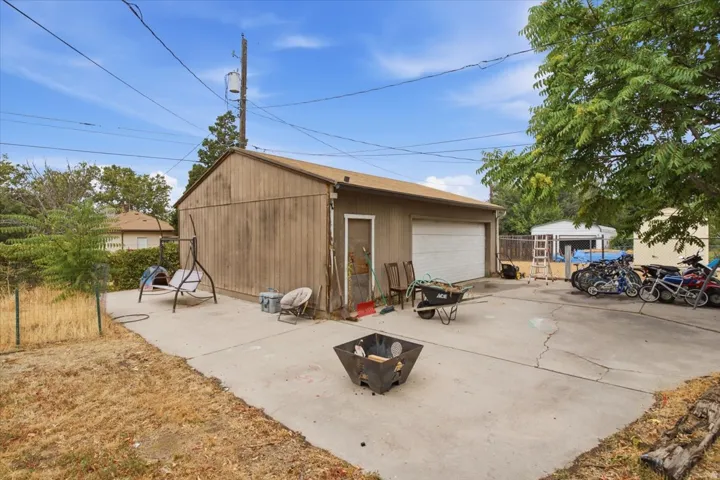 Detached garage with a roll-up door and side entry, featuring a concrete pad and a wood-sided exterior