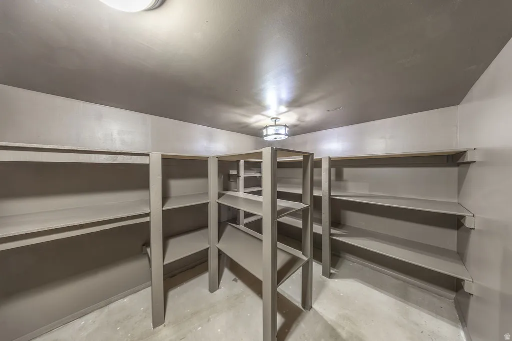 Expansive storage room featuring built-in shelving, concrete flooring, and flush-mount lighting fixtures