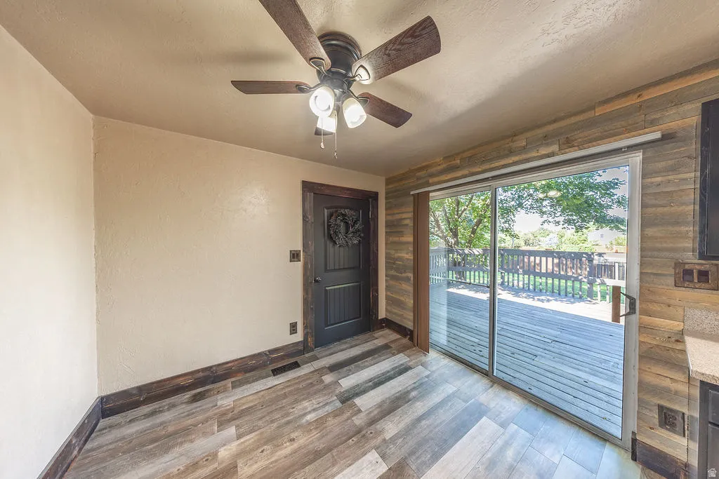 Interior space featuring wood-finish flooring, a contemporary ceiling fan with lighting, and a dark wood paneled door