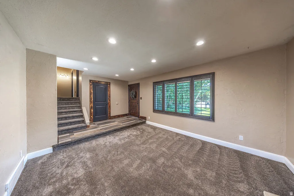 Spacious living area featuring neutral-toned carpeting and recessed lighting