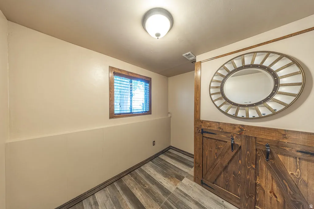 Compact space featuring wood-finish flooring, a window with horizontal blinds, and a flush mount ceiling light