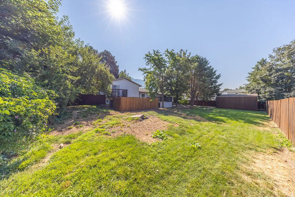 Expansive outdoor space featuring a sloped lawn, mature trees, and privacy fencing