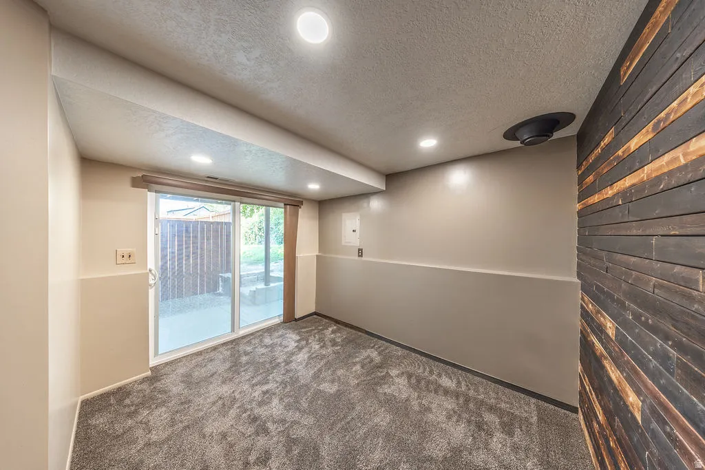 Inviting room featuring a modern wood slat accent wall, recessed lighting, and soft gray carpeting