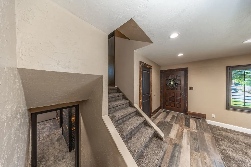 Entryway featuring wood-finish flooring, a paneled front door with dark trim, recessed ceiling lighting, and a textured wall finish