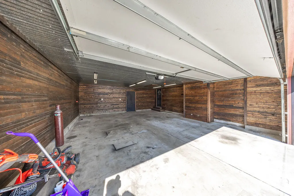 Spacious garage with concrete flooring and wood-paneled walls