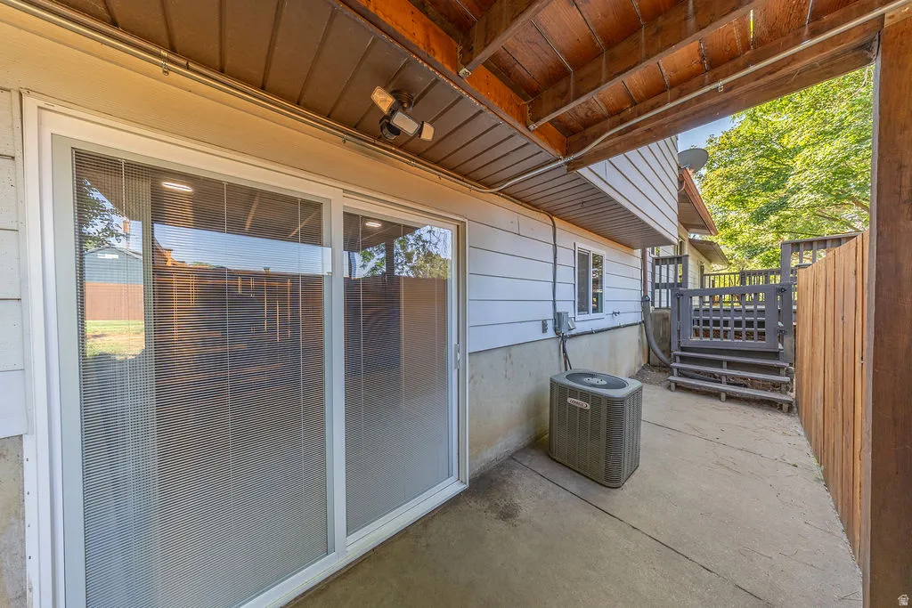 Concrete patio with a wooden privacy fence, leading to outdoor stairs with a decorative gate