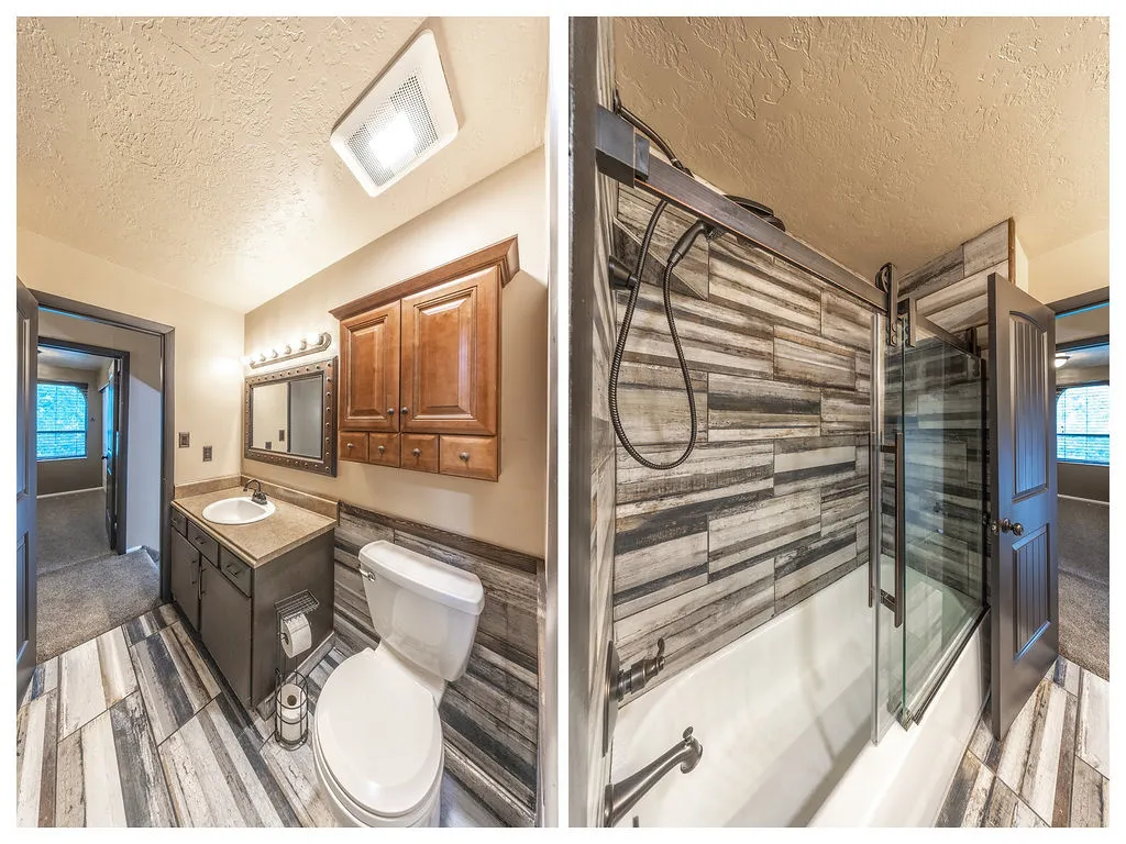 Bathroom featuring a single vanity with an integrated sink, wood-finish flooring, a wall-mounted wood cabinet, a white toilet, and a bathtub with a sliding glass enclosure