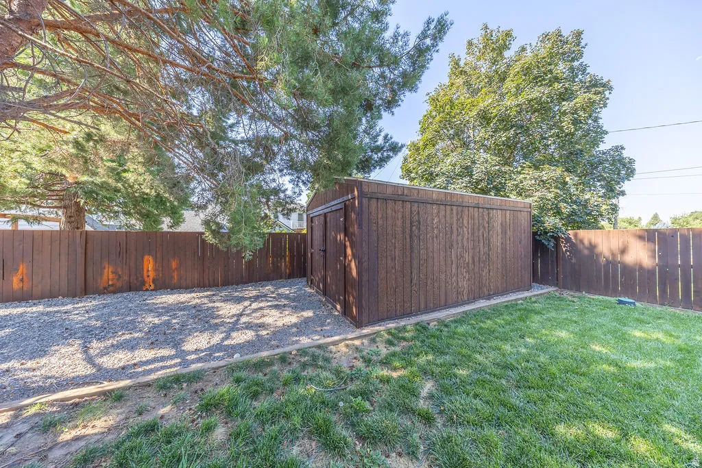 Backyard space featuring a storage shed, gravel area, and a grassy lawn