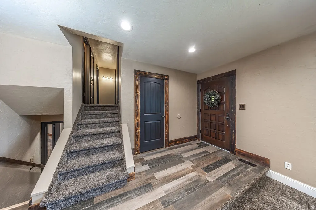 Entryway featuring multi-toned wood-finish flooring with a textured wood-paneled door