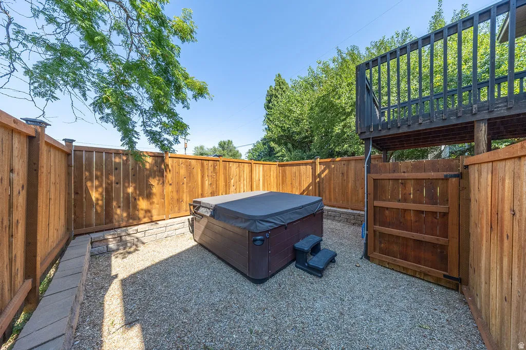 Outdoor spa area with a dark brown hot tub, surrounded by light wood fencing