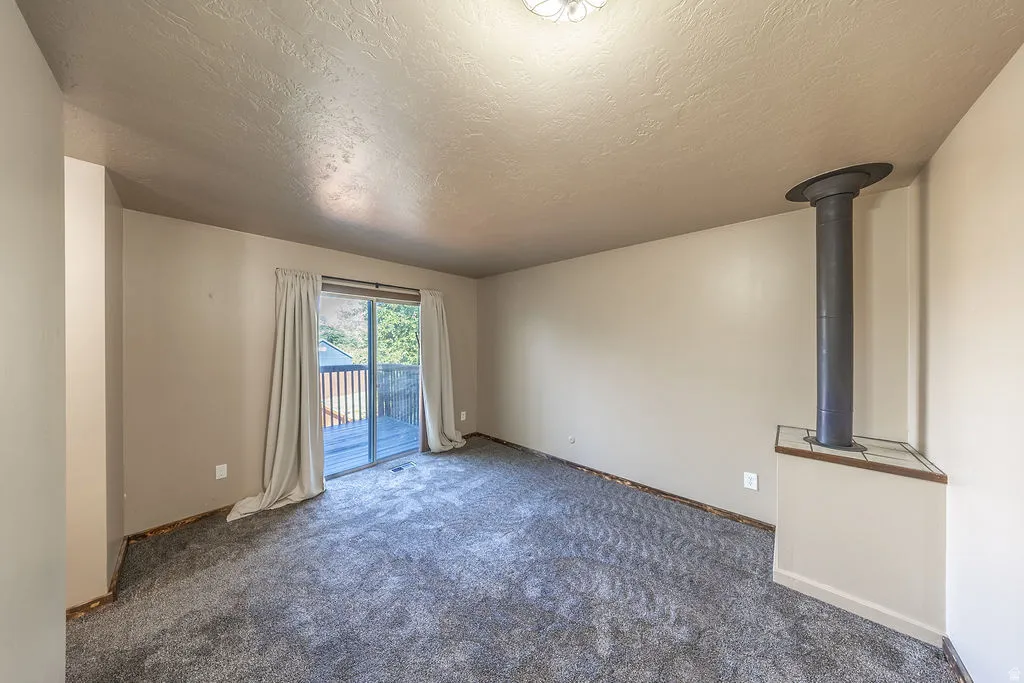 Spacious room featuring gray textured carpeting and neutral wall paint