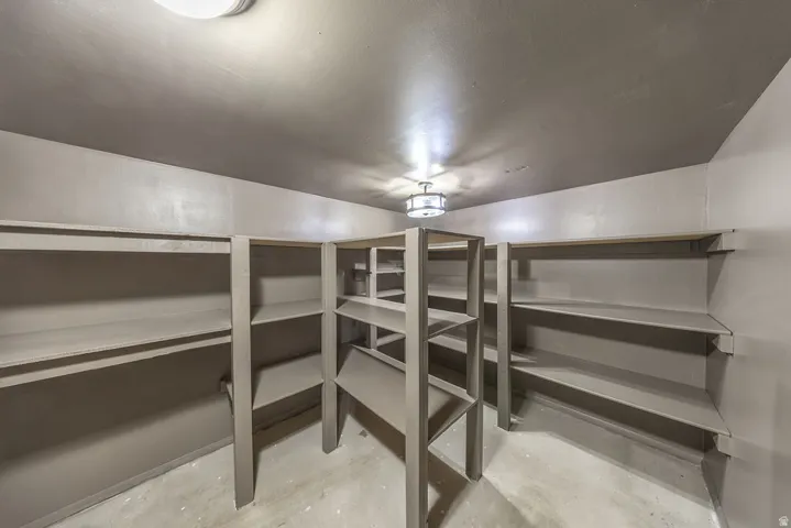 Expansive storage room featuring built-in shelving, concrete flooring, and flush-mount lighting fixtures