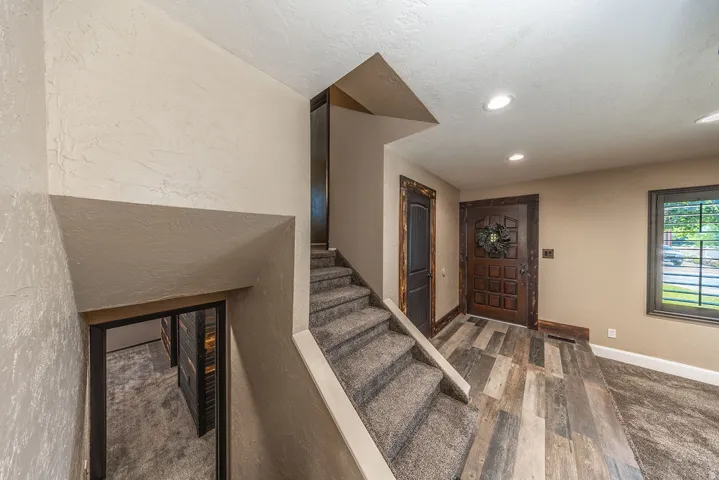 Entryway featuring wood-finish flooring, a paneled front door with dark trim, recessed ceiling lighting, and a textured wall finish