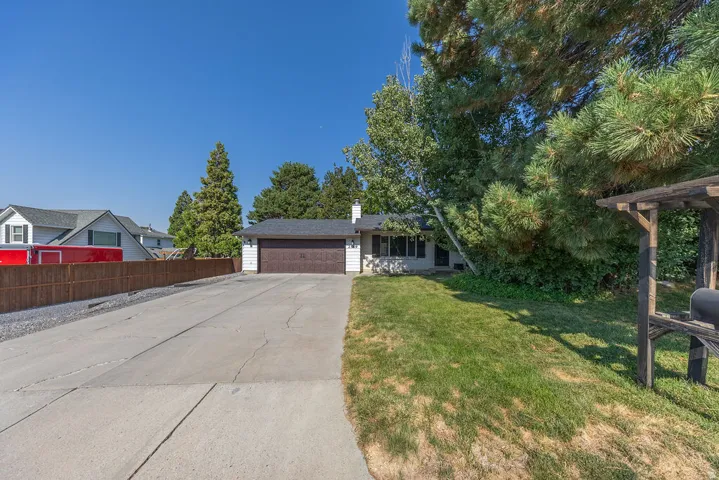 Single-story residence featuring a two-car garage with a wood-finish door, a concrete driveway, and a front facade with multiple windows