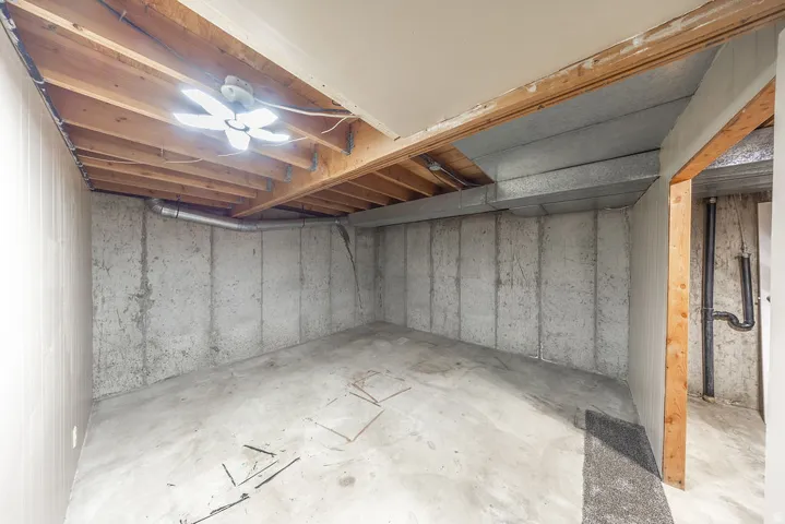 Unfinished basement space featuring exposed concrete walls and flooring, open ceiling joists, and visible ductwork