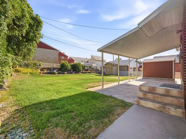 Expansive grassy yard with a covered patio and concrete steps