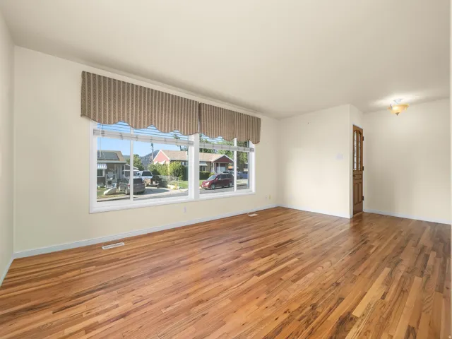 Hardwood flooring, painted walls, large window, wood-paneled door, ceiling light fixture