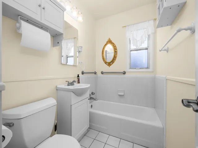 White-tiled bathtub with a wall-mounted grab bar