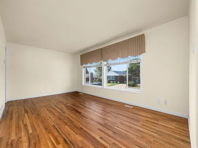 Expansive room featuring wood-finish flooring, light-toned walls, and a large multi-pane window