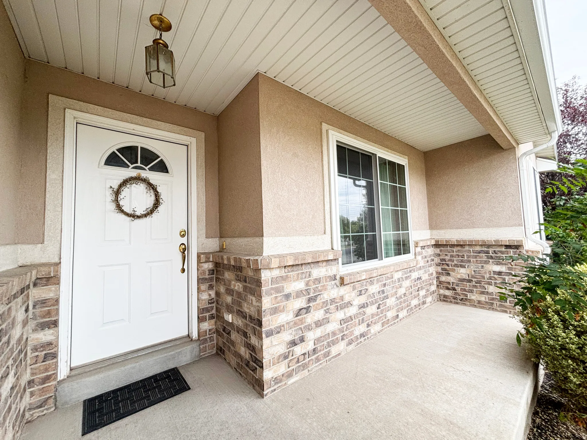 Covered concrete porch with brick and stucco exterior detailing
