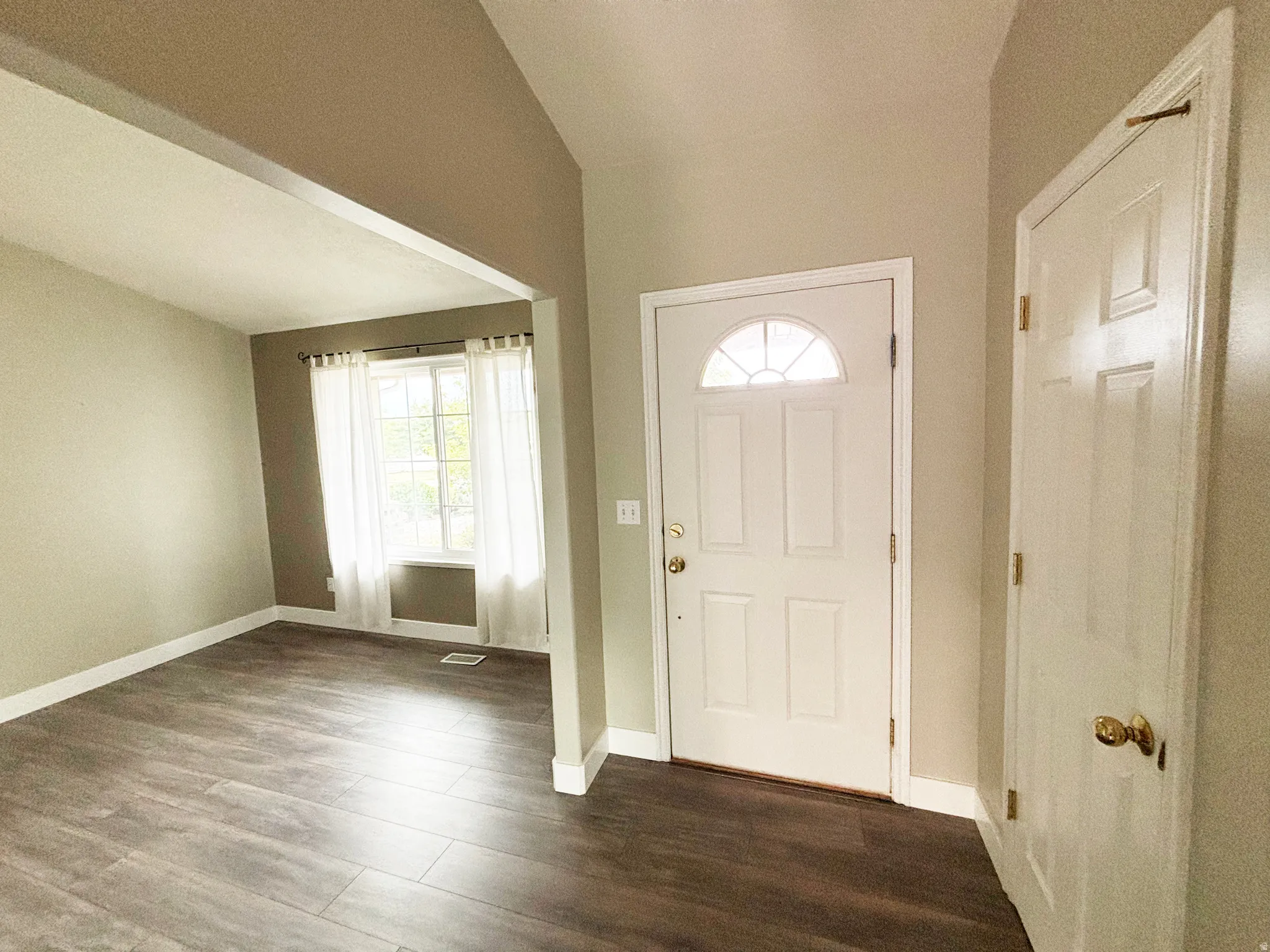 Entryway featuring a white paneled door with an arched transom, wood-finish flooring, and light neutral wall colors