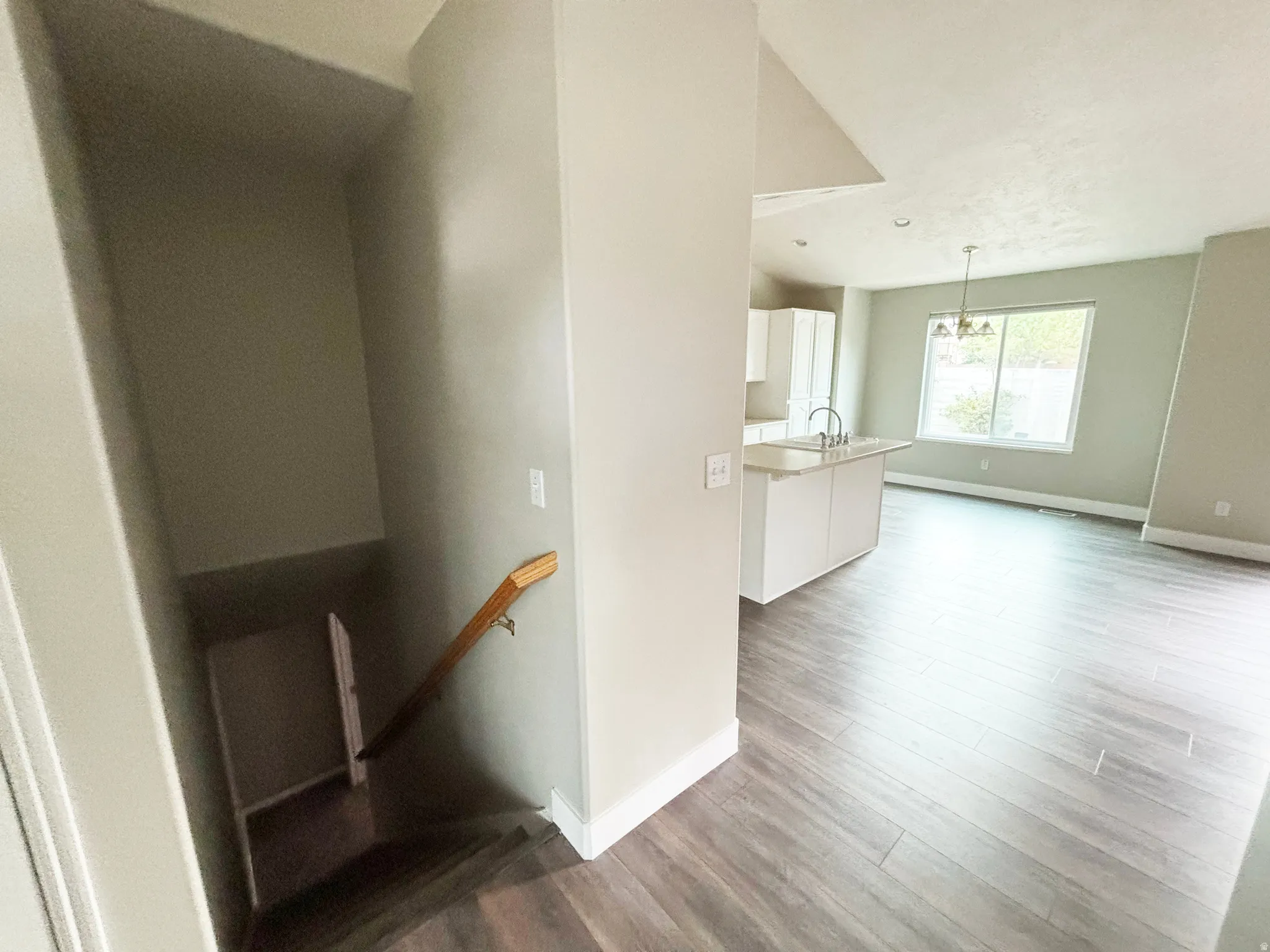 Open-concept living space with wood-finish flooring throughout, white painted walls, and abundant natural light from multiple windows
