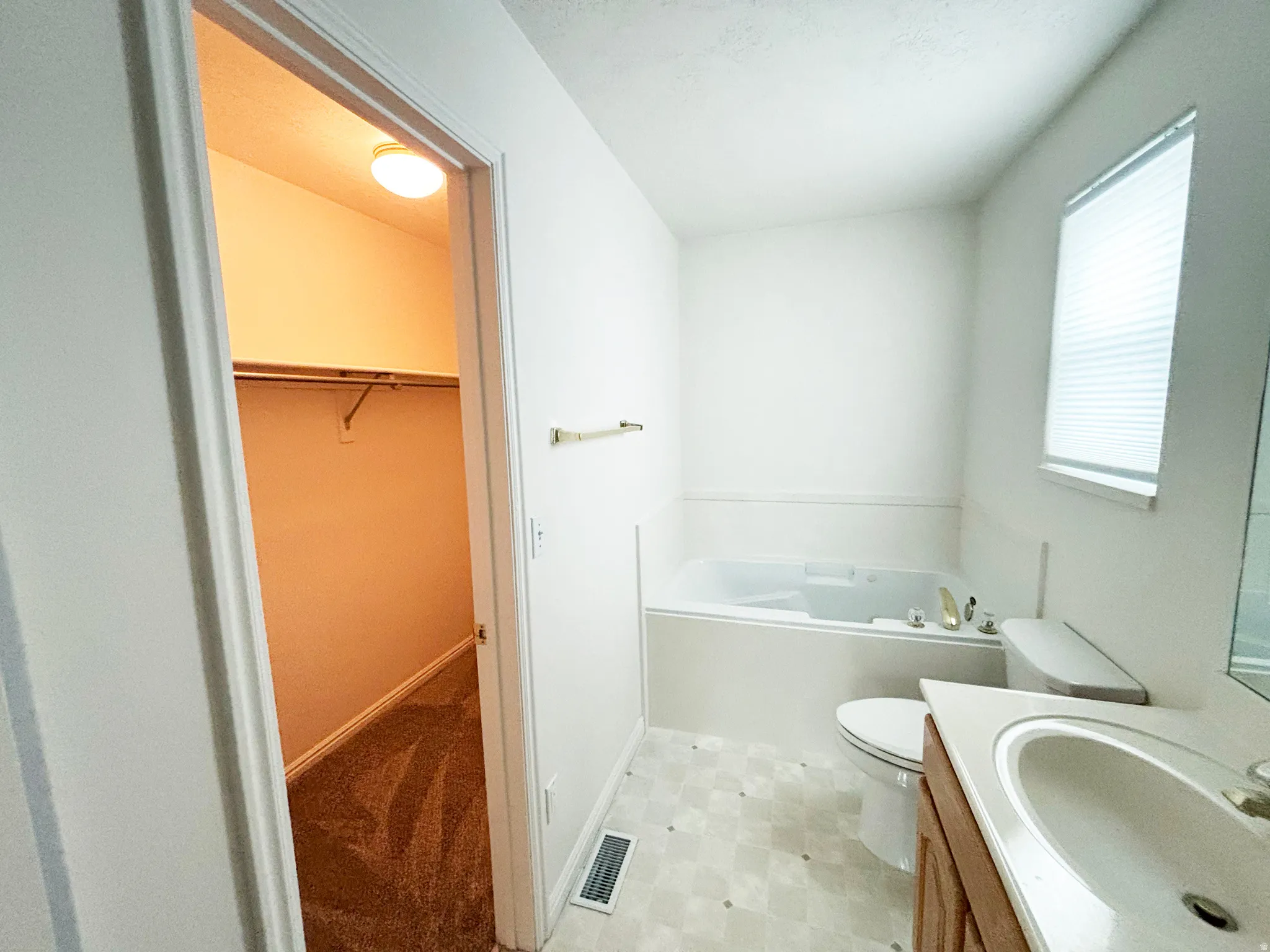 Bathroom featuring a built-in jetted tub, single vanity with integrated sink, and patterned flooring