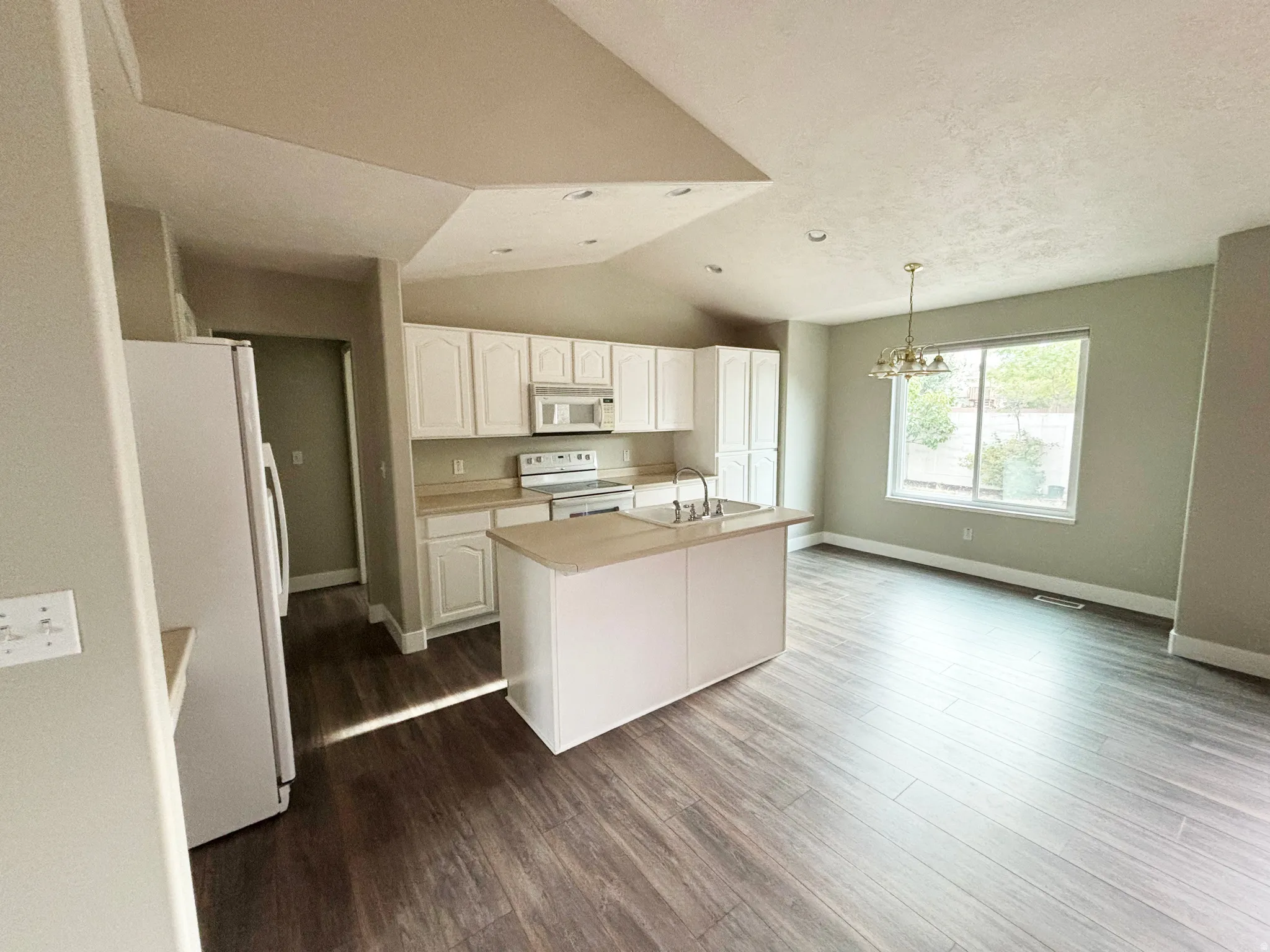 Kitchen featuring white cabinetry, a central island with an integrated sink, and stainless steel appliances