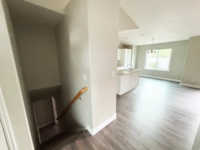 Open-concept living space with wood-finish flooring throughout, white painted walls, and abundant natural light from multiple windows