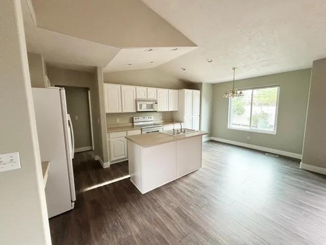Kitchen featuring white cabinetry, a central island with an integrated sink, and stainless steel appliances