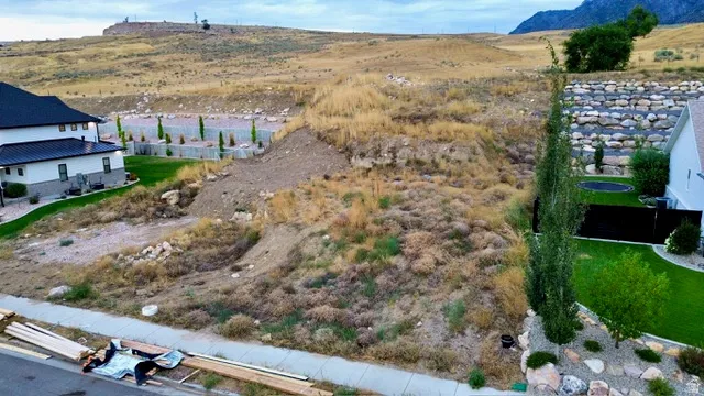 Expansive sloped lot featuring natural ground cover and a concrete sidewalk