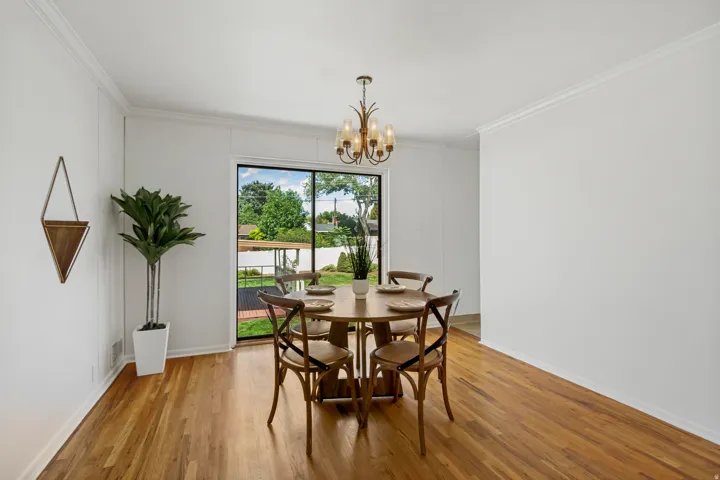 Hardwood flooring throughout, crown molding, and a chandelier with amber glass shades