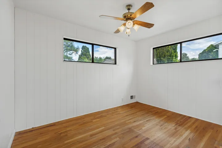 Wood-finish flooring, white paneled walls, and two horizontal windows
