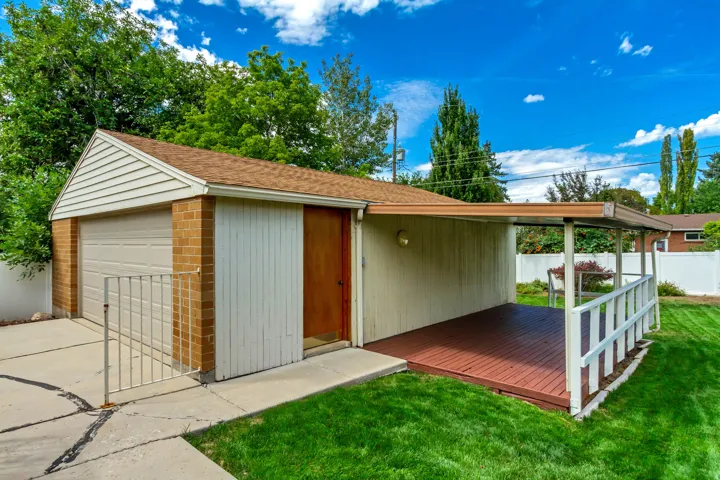 Detached garage with brick accents, an overhead door, and a shingle roof