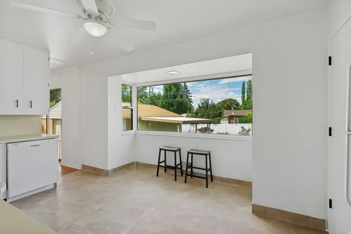 Tile flooring, built-in white cabinetry, dishwasher, ceiling fan, and large picture window