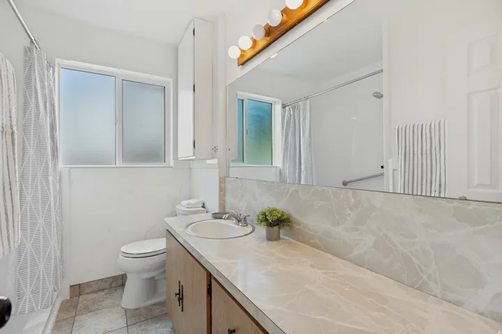 Vanity with a single basin sink, integrated countertop, and an expansive mirror