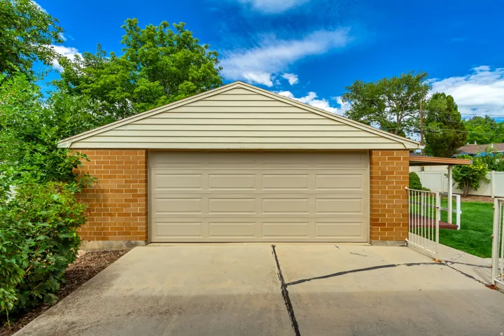 Attached garage with a panel-style door, brick and siding exterior, and a concrete driveway