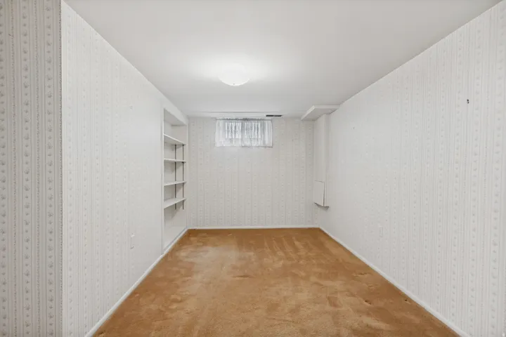 Recessed built-in shelving, textured wall covering, and a flush-mount ceiling light fixture